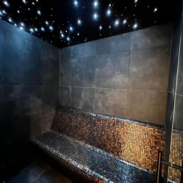 Spa‑inspirert rom med mosaikkfliser, benk og tak med stjernelys som gir rolig atmosfære.